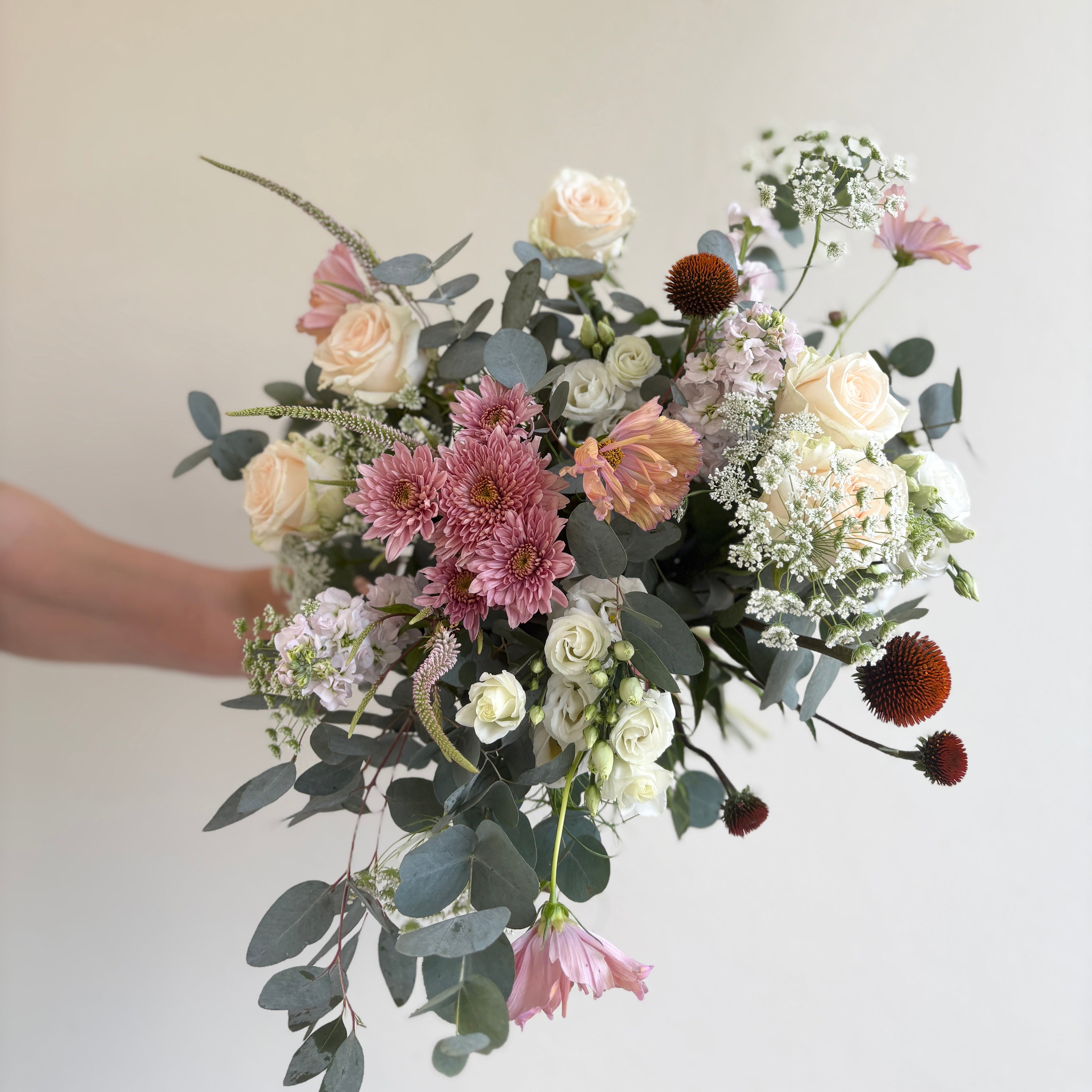 Bouquet of flowers held by a person against a plain background