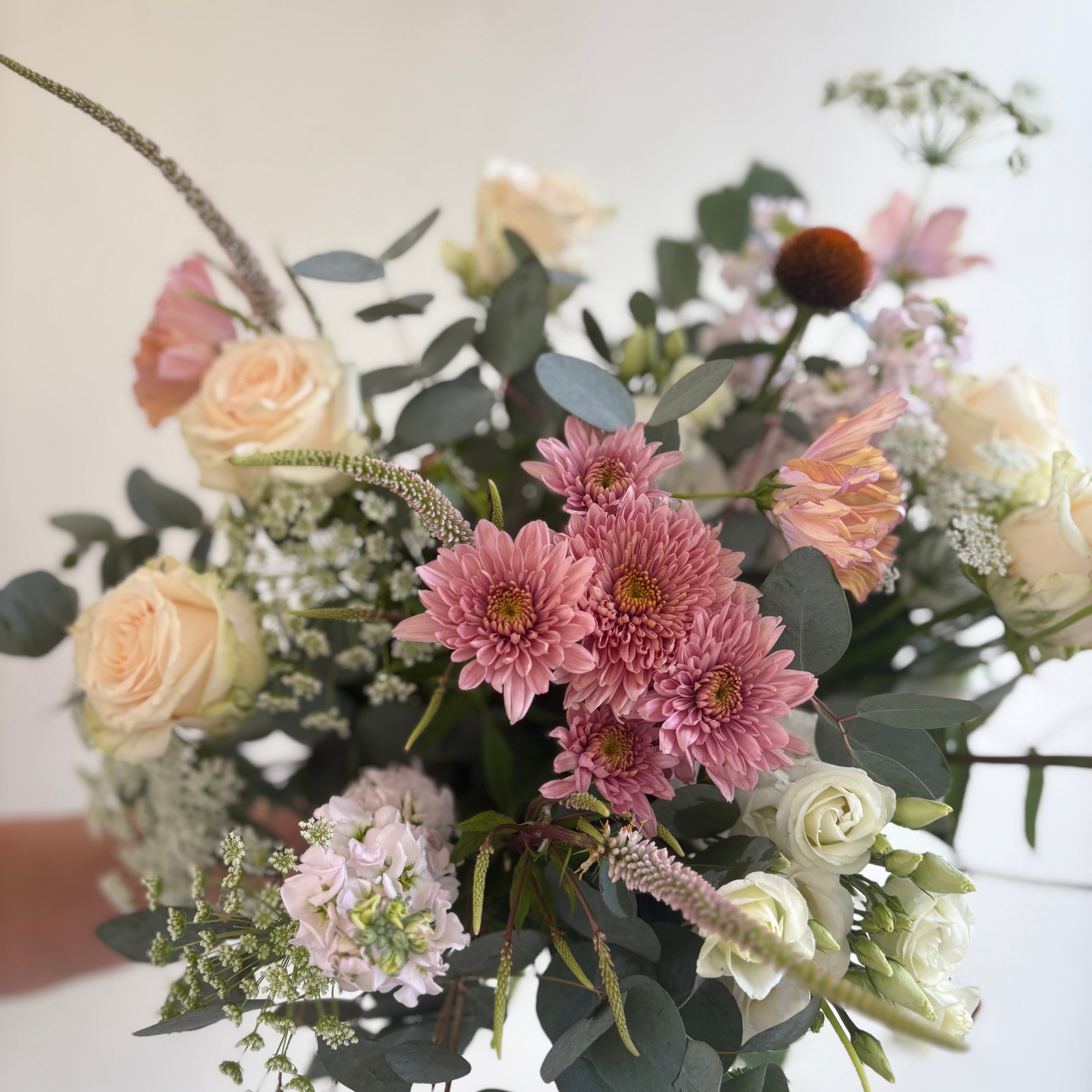 Bouquet of flowers with pink, white, and green colors on a light background