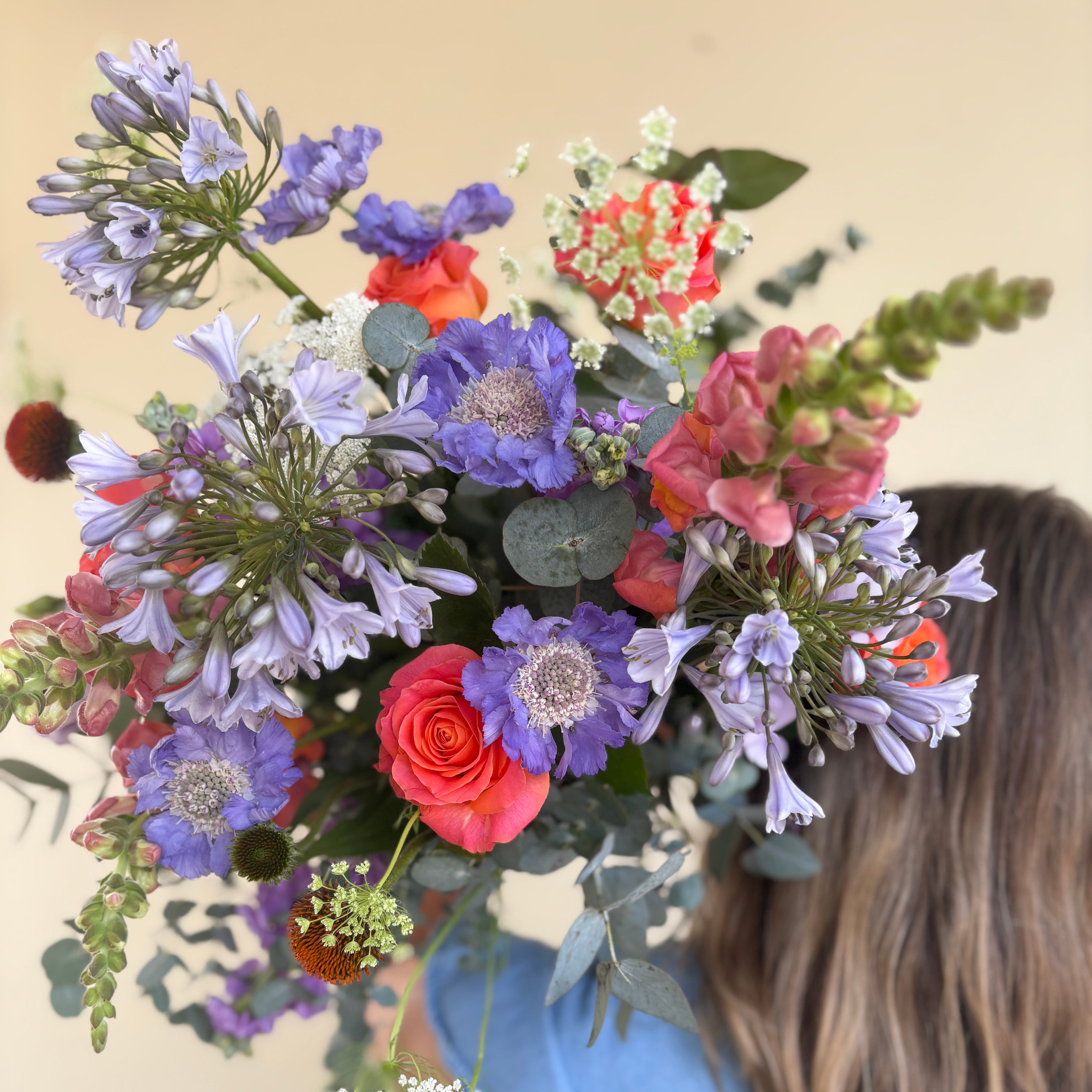 Person holding a colorful bouquet of flowers with a light background