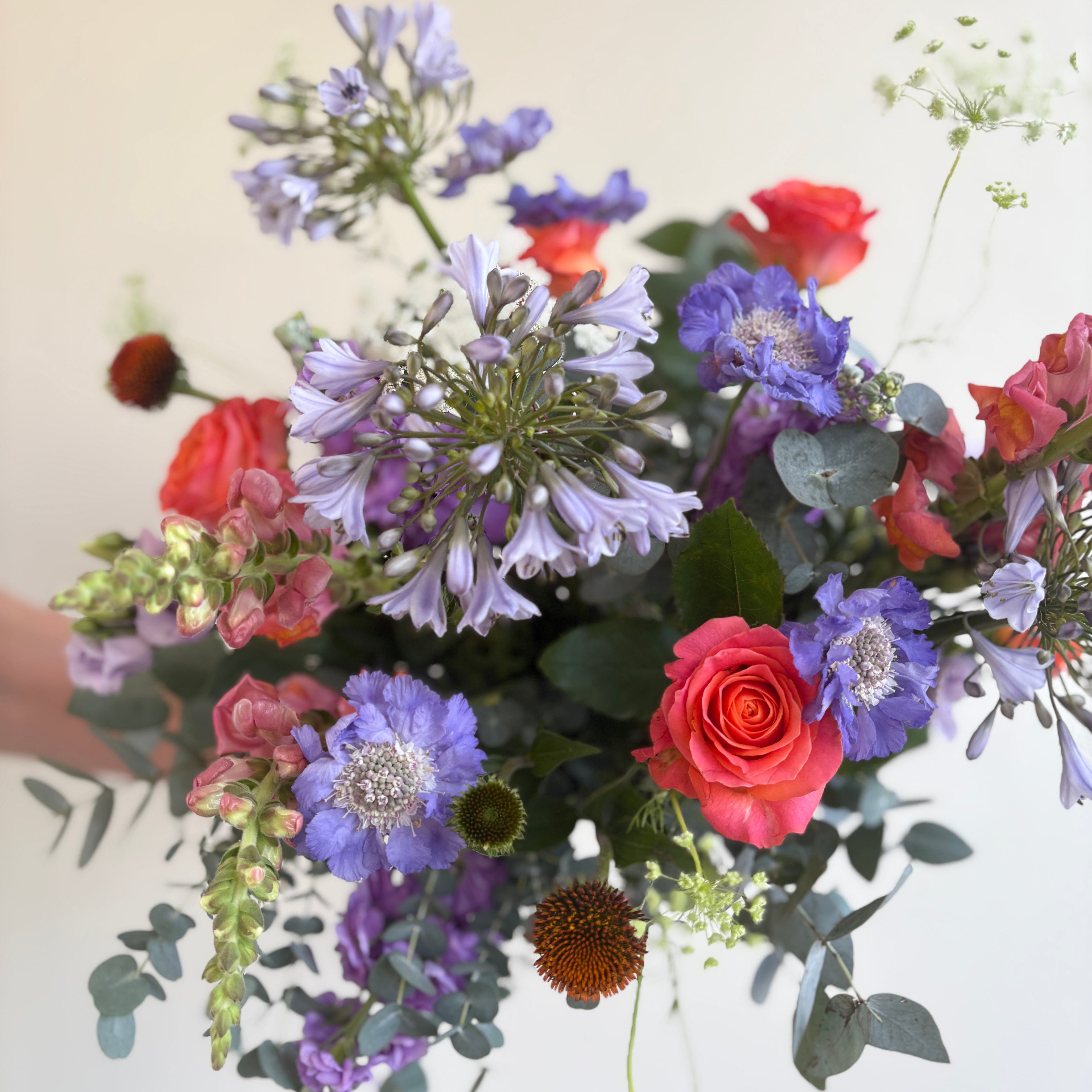 Bouquet of colorful flowers held by a person against a light background